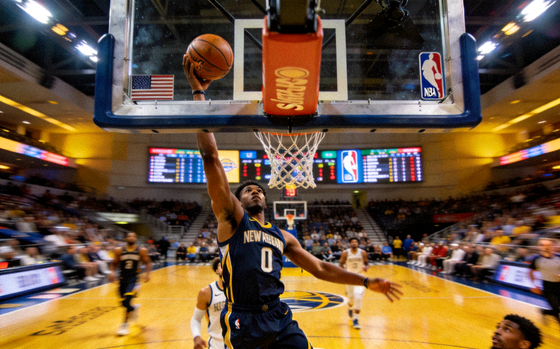 NBA篮球比赛现场，球员在篮下完成上篮动作
